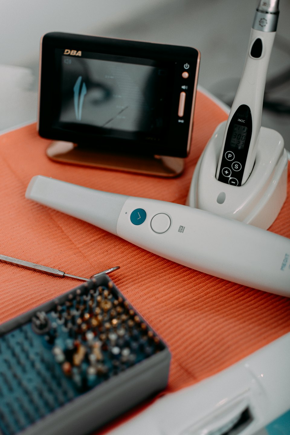 Modern dental tools and monitor on an orange tray.