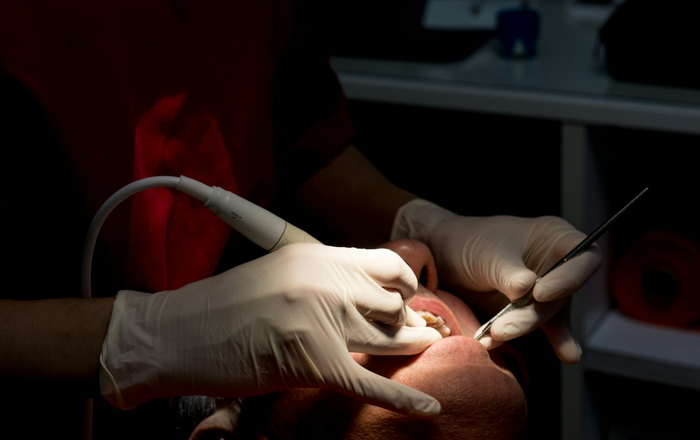 Dentist working on a patient's teeth with dental tools.