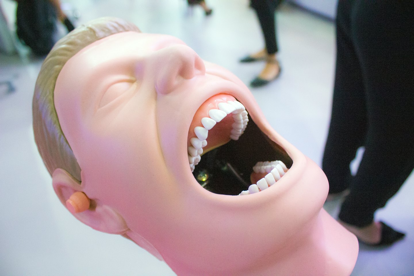 Medical training dummy head with mouth open showing teeth.